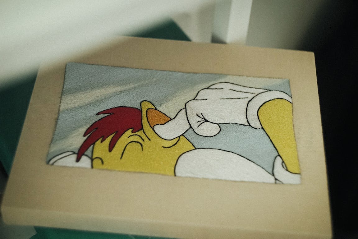 An embroidery shows a character plugging their ears.
